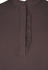 Hnědý top se volánkovou légou, zapínáním na knoflík a měkkou, texturovanou tkaninou s kulatým výstřihem. Jednoduchý design, bez vzorů.