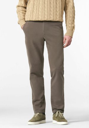 Braune Baumwollhosen mit schlanker Passform und Seitentaschen, kombiniert mit olivgrünen Wildledersneakern und einem beigen Strickpullover.