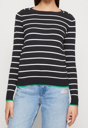 Navygestreifter Pullover mit weißen horizontalen Streifen, Schulterknöpfen, grünem Saum und taillierten Ärmeln, kombiniert mit hellblauen Jeans.