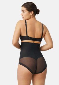 Lencería negra con tirantes ajustables, cintura alta y detalles de paneles de malla transparente en la parte trasera. Textura de tela suave con un diseño ajustado al cuerpo.