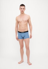 Boxeri de culoare albastru deschis cu talie neagră pe care este brodat logo-ul "Versace". Material din bumbac elastic, design ajustat, lungime până la mijlocul coapsei. Fără modele sau accente.