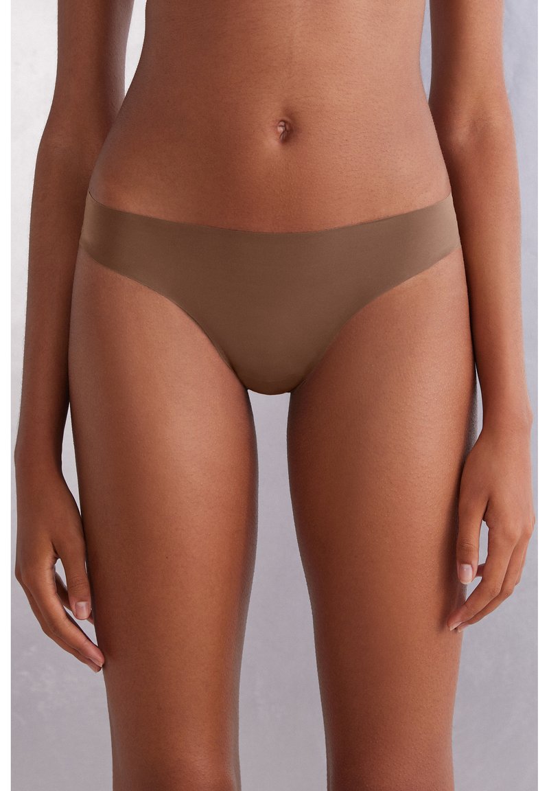 Bruna sömlösa bikiniunderkläder med en slät yta och lågt midjesnitt, med en tunn midjeband och minimal täckning på sidorna.
