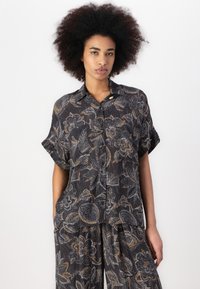 Korte mouw blouse met een donker bloemenpatroon met abstracte bloemen in wit en goud. Gemaakt van lichtgewicht stof, met een knoopsluiting bij de kraag.