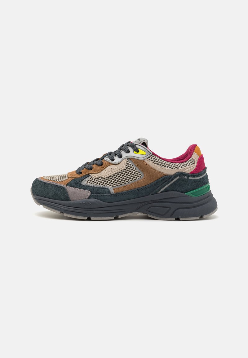 Baskets multicolores présentant un mélange de mesh, de daim et de cuir. Principalement vert foncé, marron, avec des accents de rouge, jaune et orange.