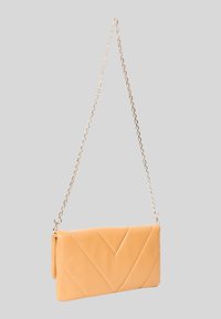 Clutch in pelle pesca con trapuntatura a chevron, presenta una tracolla in catena dorata e una forma rettangolare, texture liscia e design minimalista.