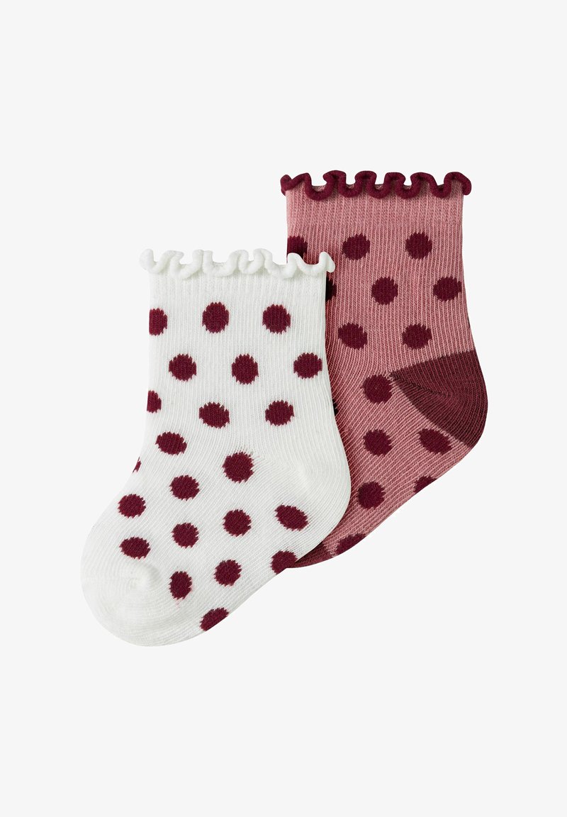 Deux chaussettes pour bébé avec des pois bordeaux, une blanche avec un bord froncé, une rose poussiéreuse avec un bout plus foncé et un bord froncé.