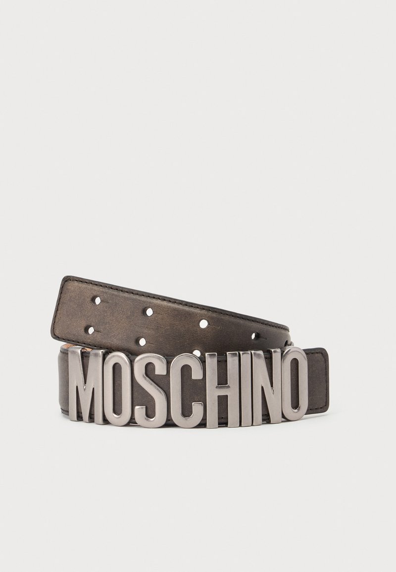 Ceinture en cuir marron foncé avec de grandes lettres argentées formant "MOSCHINO" comme boucle sur fond blanc.