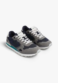 Zapatillas grises y marinas con parte superior de malla y gamuza, cordones blancos, detalles en color azul verdoso y una suela de goma con un patrón de banda de rodadura texturizado.