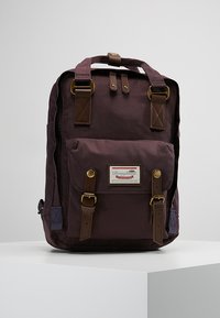 Dark purple backpack made of durable fabric, featuring brown leather accents, dual top handles, front flap pocket, and a logo patch.