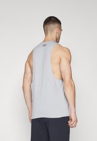 Top sin mangas gris hecho de tela ligera, con cuello redondo y aberturas laterales, con un logo cerca del escote.