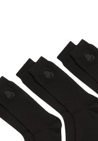 Calcetines de algodón negros con textura acanalada, que presentan un pequeño logo en gris oscuro. Diseñados para un ajuste ceñido con talones reforzados.
