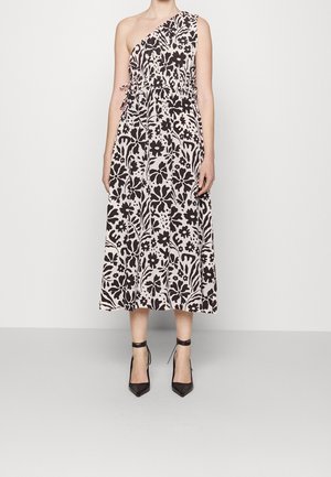 Midi-jurk met één schouder en een zwart-wit bloemenpatroon, getailleerde taille, gecombineerd met zwarte enkellaarsjes met enkelbandje aan model tegen een witte achtergrond.