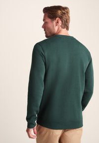 Green sweatshirt with a round neckline and ribbed cuffs, made of soft material, featuring a plain texture and fitted silhouette.
