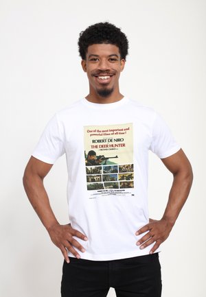 Hvid bomulds T-shirt med et trykt filmplakat for "The Deer Hunter," med farverige stillbilleder og tekst i midten.