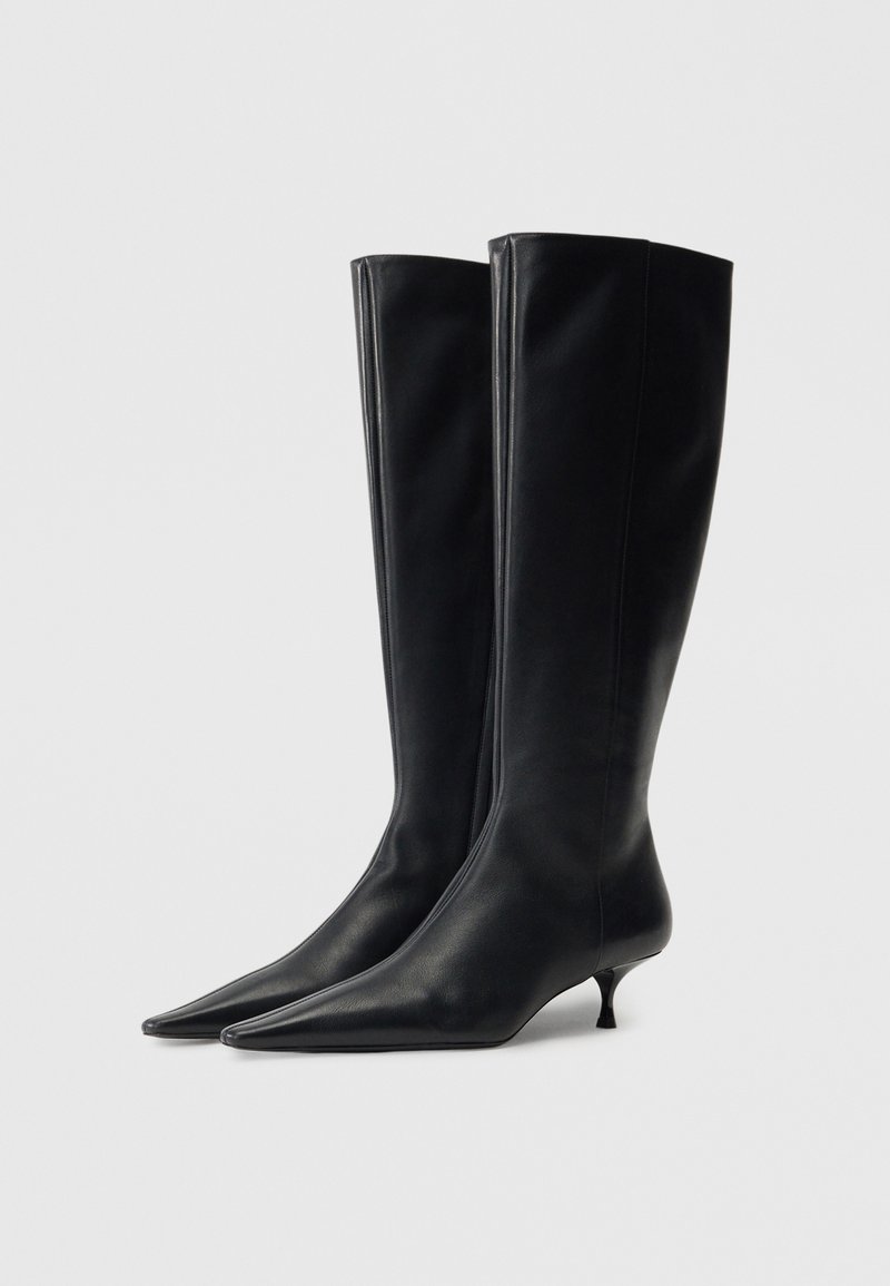 Svarta läderstövlar som når upp till knäna, med spetsig tå och smal kitten-häl, har en slät yta och en elegant, åtsittande design.