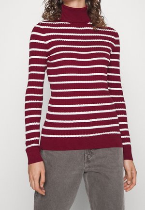 maglione a collo alto bordeaux con strisce orizzontali bianche, texture a coste e design aderente, abbinato a indumenti grigi.