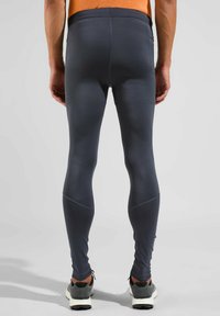 Donkergrijze sportlegging met een gladde textuur, voorzien van een hoge tailleband en een taps toelopende pasvorm die tot de enkels reikt.