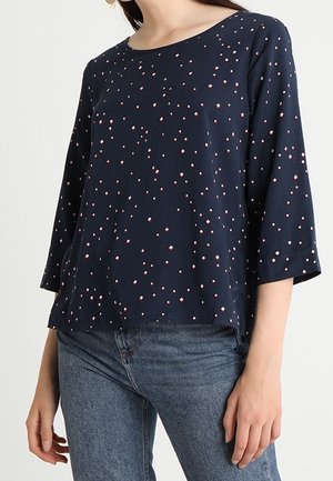 Maglietta di cotone blu navy con colletto rotondo, maniche a tre quarti e motivo a pois rosa su tutta la superficie. Orlo dritto, vestibilità comoda.