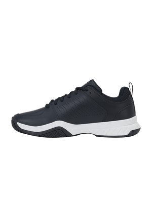 Baskets de sport noires avec semelle blanche, panneau latéral perforé, lacets noirs et languette au talon, montrées de profil sur fond blanc.