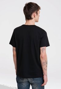 Camiseta de algodón negra con mangas cortas, cuello redondo y un corte relajado. La tela parece suave, sin patrones o acentos visibles.