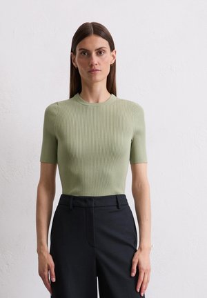 Ribbed, short-sleeve top in light green, featuring a crew neck; paired with dark, tailored pants. Smooth texture, form-fitting design.