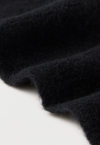 Sort uldstof med en blød, tekstureret overflade, der har et let dunet udseende og en blid drapering.