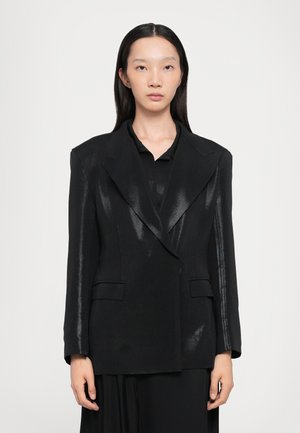 Black blazer made from a textured fabric featuring a glossy sheen, oversized shoulders, notched lapels, and two front pockets.
