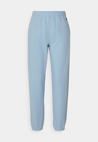 Modré teplákové kalhoty z měkké látky s elastickým pasem, zužujícími se lemy a malým logem na boku.