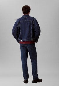 Tumesinises toonis teksajope lõdva lõikega, laiad õlad, nööbiga detailid ja külgpaneeli disain, mida kannab sobivate teksadega.