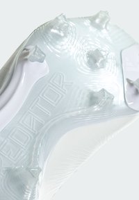 Suola di scarpone da calcio con tacchetti in plastica bianca traslucida, caratterizzata da scanalature testurizzate e quattro tacche angolari per una migliore aderenza. Dettaglio in rilievo "PREDATOR".