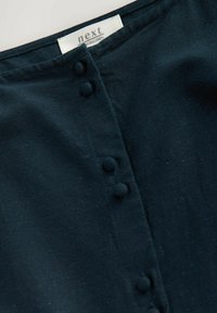 Cămașă din in de culoare bleu închis, cu o linie de gât rotundă, butoane decorative din țesătură și o suprafață netedă, ușor texturată.