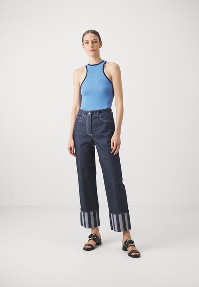 Blå ärmlös bodysuit med hög halsringning, som matchas med mörk denim byxor med vida ben och randiga mudd, samt svarta klacksandaler med blockklack.
