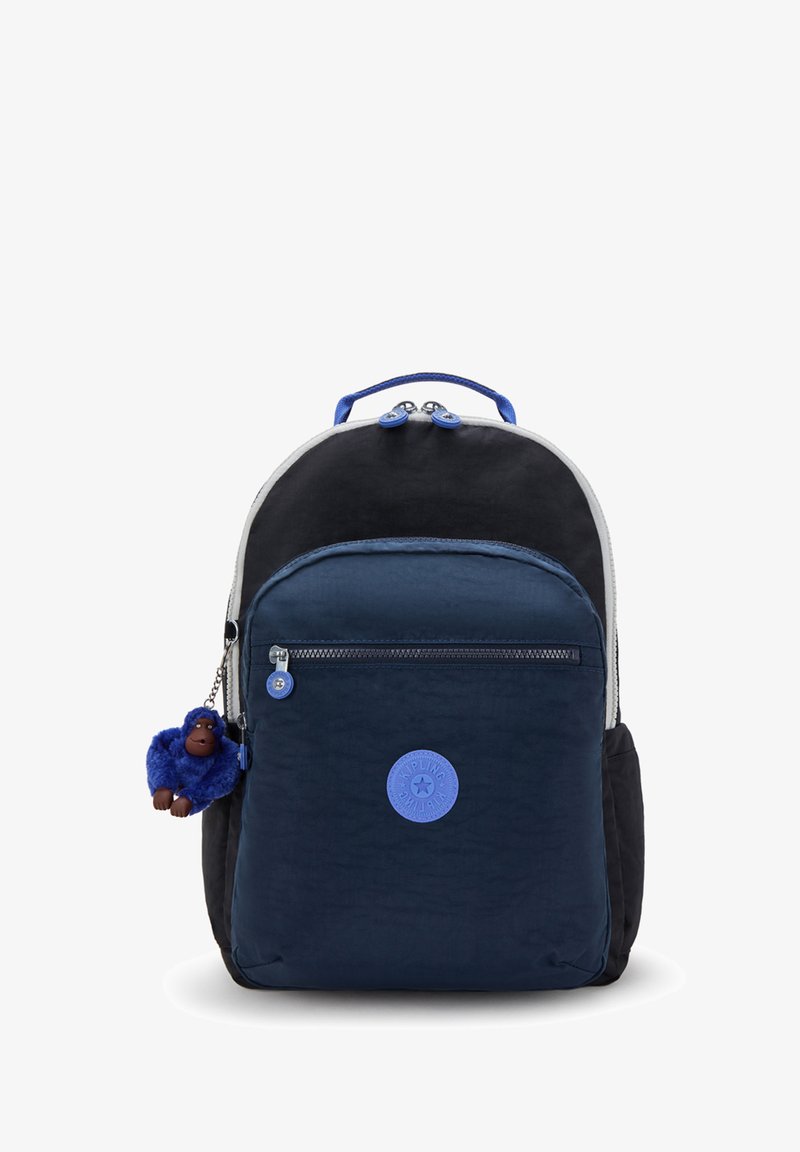Zaino navy e nero con tasca zip davanti, logo circolare blu e portachiavi a forma di scimmia di peluche blu attaccato al lato.