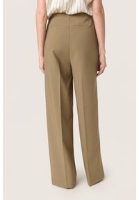 Pantaloni a vita alta e gamba larga in un tessuto marrone chiaro con una texture liscia. Presentano una vestibilità sartoriale e senza hardware visibile.