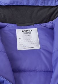 Vnitřek fialové nepromokavé bundy s měkkou černou podšívkou. Na štítku je napsáno "reima", velikost "104/4T" a obsahuje informace o předchozím majiteli.