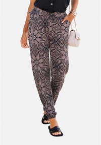 Pantalones jogger en patrón negro y salmón con cintura elástica y puños en los tobillos. Combinados con una blusa negra y sandalias planas.
