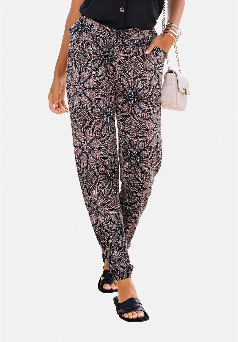 Pantalones jogger en patrón negro y salmón con cintura elástica y puños en los tobillos. Combinados con una blusa negra y sandalias planas.