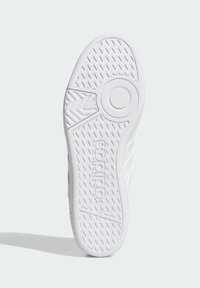 White rubber sneaker sole featuring a textured grip pattern, branding, and distinct circular accent at the center for traction.