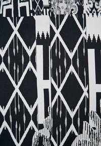 Tessuto a fantasia con design geometrici in bianco e nero, tra cui diamanti, linee e punti, con texture e motivi variabili.