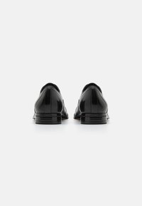 Zapatos de vestir de cuero negro con un acabado suave, punta redonda y tacón bajo apilado. Presentan un diseño elegante con detalles de costura sutiles.