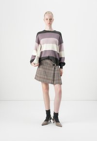 Striped sweater in purple, white, and black; plaid skirt with a belt detail; gray socks; beige pointed shoes; clutch in hand.