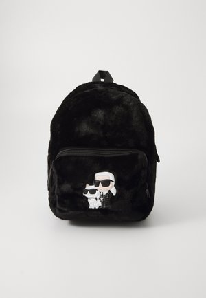 Sac à dos en fourrure noire de forme arrondie, avec une poche avant et des appliqués de personnages de dessins animés représentant un homme en lunettes de soleil et un chat blanc.