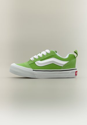 Baskets basses vertes et blanches avec des lacets blancs, un motif en forme de vague blanche sur le côté, et une semelle épaisse en caoutchouc blanc.