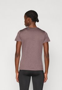 T-shirt z krótkim rękawem, dopasowany w mauve'owym kolorze, o gładkiej fakturze. Okrągły dekolt i minimalne detale szwów na dolnym brzegu.