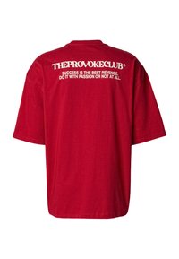Rød T-skjorte med korte ermer og løs passform, med hvit tekst trykt på baksiden som lyder "THEPROVOKECLUB®" og et sitat.
