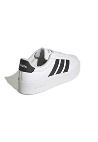 Witte sneaker met zwarte strepen, een glad leren bovenwerk, een gevoerde kraag en een dikke witte rubberen zool met geperst logo.
