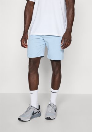 Ljusblå träningsshorts i en avslappnad passform, matchade med en vit t-shirt med rund hals, grå sneakers och vita strumpor med en svart logga.
