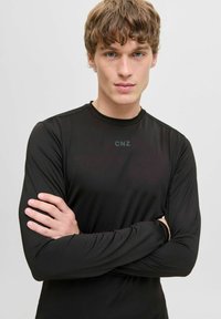 Schwarzes Langarm-Athletikoberteil aus glattem Material mit Rundhalsausschnitt und dezentem "CNZ"-Logo auf der Brust.