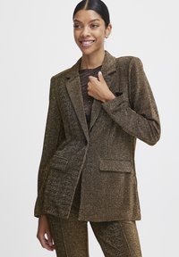 Metallisch goldener Blazer mit strukturierter Oberfläche, überzogen mit einreihiger Knopfleiste, zwei vorderen Taschen und einem einzigen Knopfverschluss.