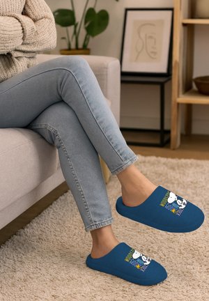 Blue slip-on slippers with a soft texture, featuring a cartoon graphic and colorful text on the upper. Worn with light blue jeans.